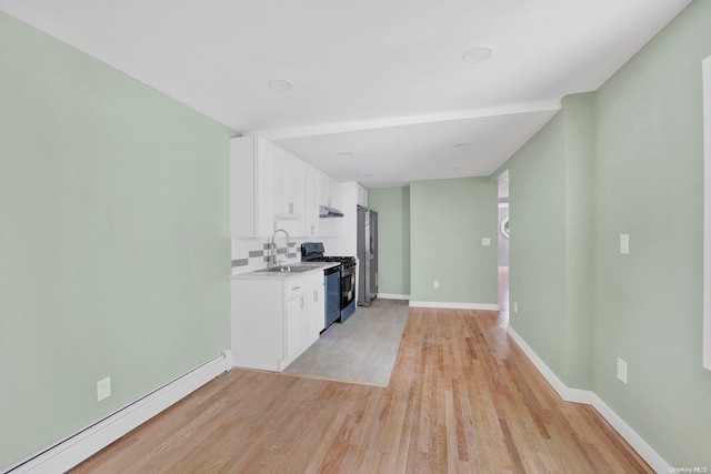 kitchen featuring sink, black stove, baseboard heating, light hardwood / wood-style flooring, and white cabinets