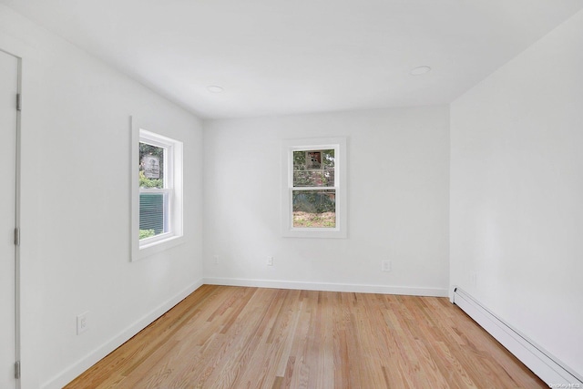 empty room featuring plenty of natural light, light hardwood / wood-style floors, and baseboard heating