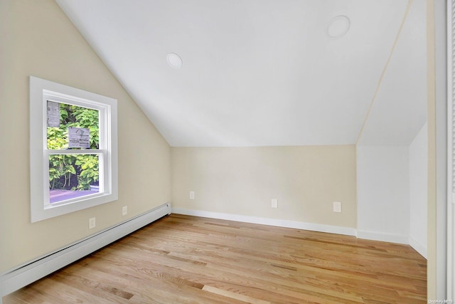 additional living space with light hardwood / wood-style floors, baseboard heating, and vaulted ceiling