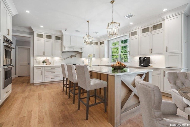 kitchen with white cabinets, pendant lighting, a kitchen island, and double oven