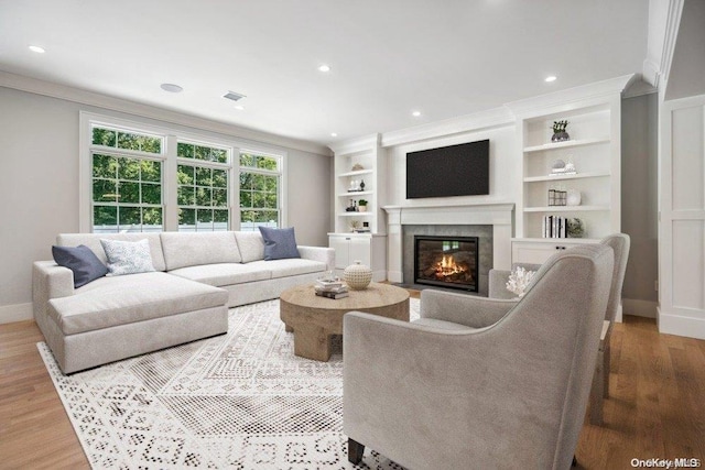 living room featuring wood-type flooring, built in shelves, and ornamental molding