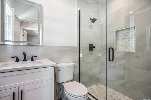 bathroom featuring vanity, an enclosed shower, tile walls, and toilet