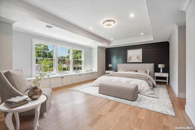 bedroom featuring light hardwood / wood-style floors, a raised ceiling, and ornamental molding