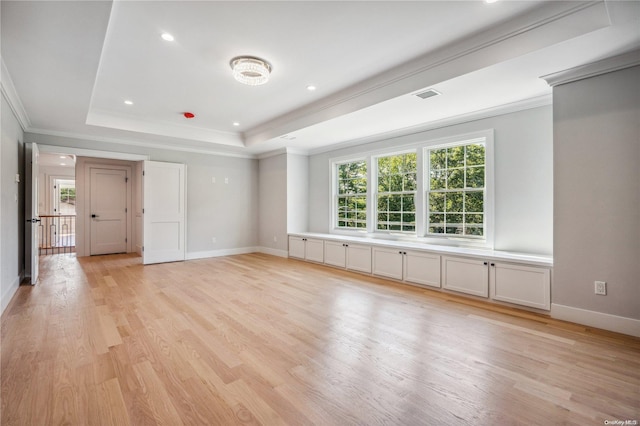 empty room featuring light hardwood / wood-style floors, a raised ceiling, a wealth of natural light, and crown molding