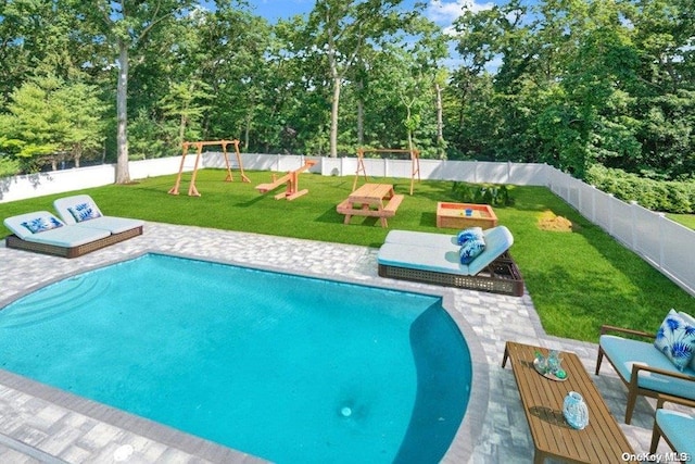 view of pool featuring a lawn, a playground, and a patio