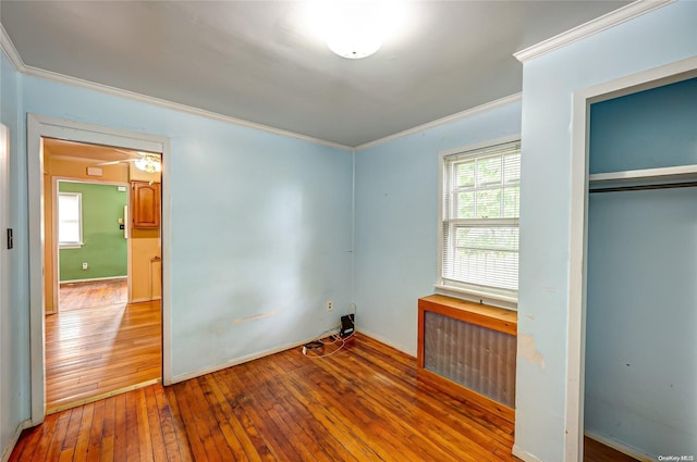 unfurnished bedroom with radiator, hardwood / wood-style flooring, ornamental molding, and a closet