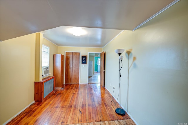 hallway featuring hardwood / wood-style floors, radiator heating unit, and ornamental molding