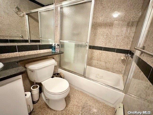 full bathroom with combined bath / shower with glass door, vanity, toilet, and baseboard heating