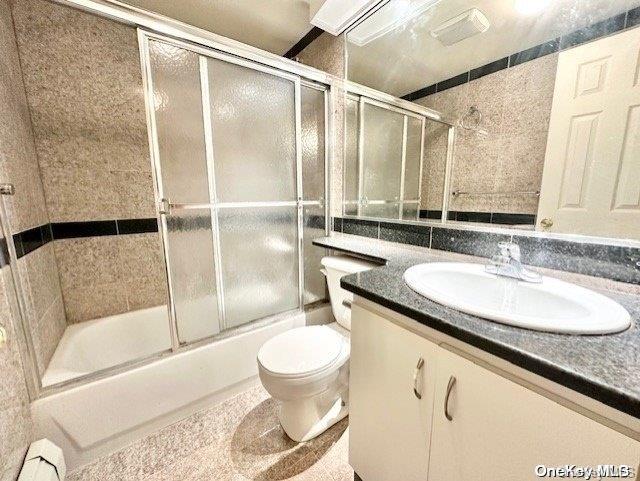 full bathroom with combined bath / shower with glass door, vanity, and toilet