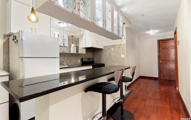 kitchen featuring pendant lighting, custom exhaust hood, a breakfast bar, black range oven, and white refrigerator