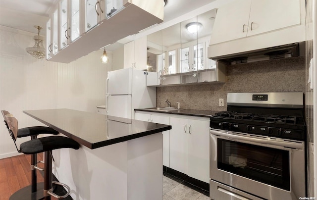 kitchen featuring gas stove, light hardwood / wood-style flooring, white fridge, pendant lighting, and white cabinets