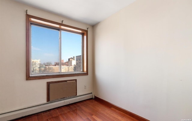 empty room with wood-type flooring and baseboard heating