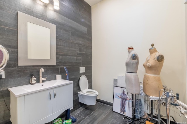 bathroom with vanity, toilet, and tile walls