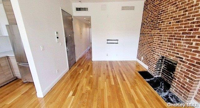 hallway featuring light hardwood / wood-style flooring and brick wall