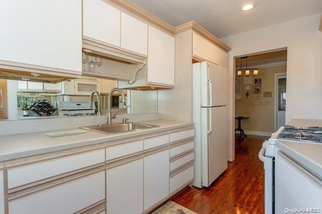 kitchen featuring white appliances, white cabinetry, dark wood-type flooring, and sink