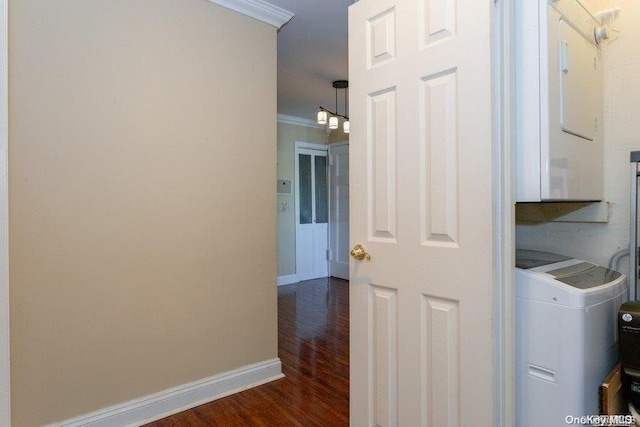 laundry area featuring dark hardwood / wood-style flooring, stacked washer / dryer, and ornamental molding