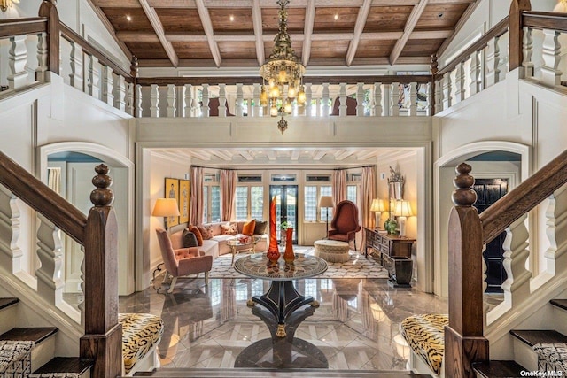 entrance foyer with beam ceiling, a chandelier, wood ceiling, and a high ceiling