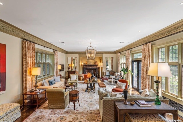 living room with hardwood / wood-style flooring, plenty of natural light, an inviting chandelier, and ornamental molding