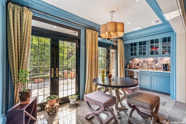 interior space with french doors, beverage cooler, bar area, crown molding, and a chandelier