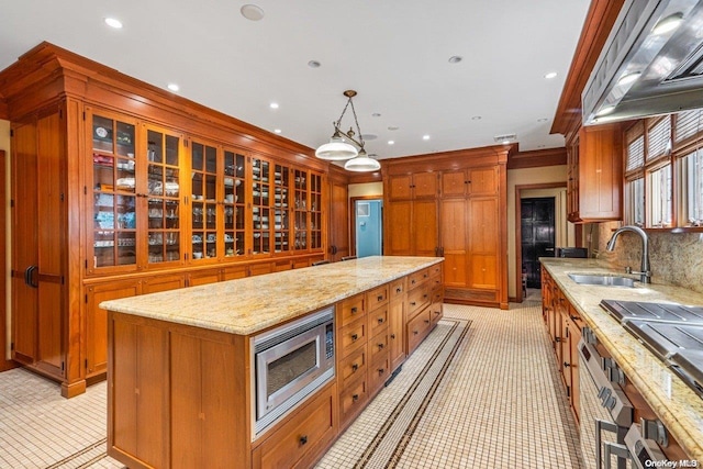 kitchen featuring decorative backsplash, stainless steel microwave, sink, a center island, and hanging light fixtures