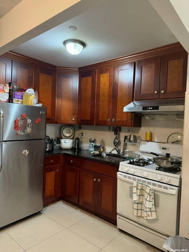 kitchen with light tile patterned flooring, white range with gas stovetop, and stainless steel refrigerator