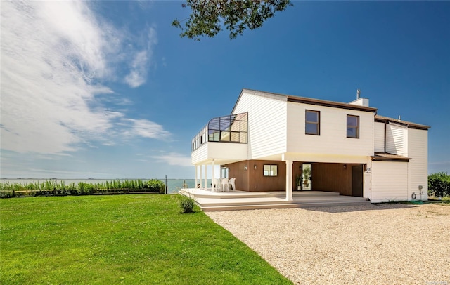 rear view of house featuring a lawn, a patio area, and a balcony