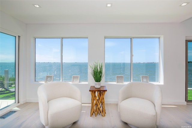 living area featuring light wood-type flooring and a water view