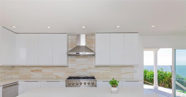 kitchen featuring wall chimney exhaust hood, white cabinetry, plenty of natural light, and stainless steel appliances