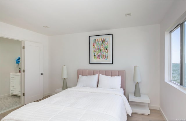 bedroom featuring a water view and light hardwood / wood-style flooring