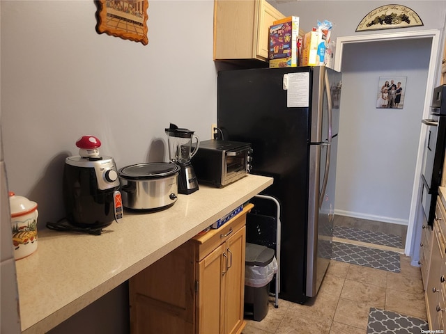 kitchen featuring light brown cabinetry, light tile patterned floors, and stainless steel refrigerator