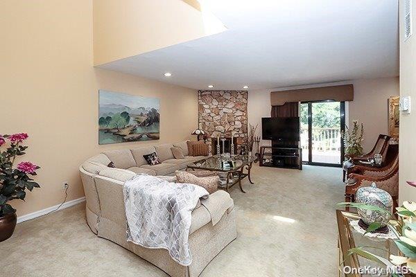 carpeted living room with a stone fireplace