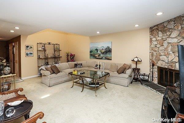 living room featuring carpet floors and a stone fireplace