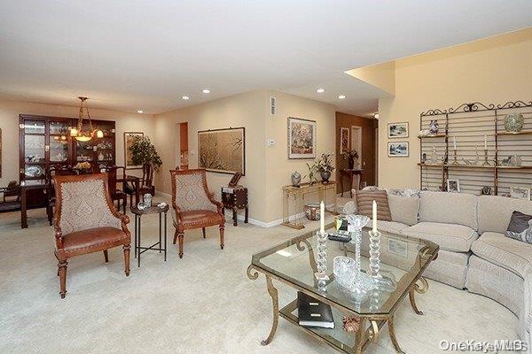 carpeted living room with an inviting chandelier