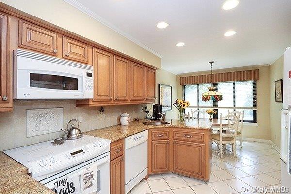 kitchen featuring white appliances, backsplash, sink, ornamental molding, and decorative light fixtures