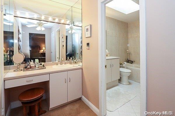 full bathroom featuring vanity, ceiling fan, tile patterned flooring, toilet, and tiled shower / bath