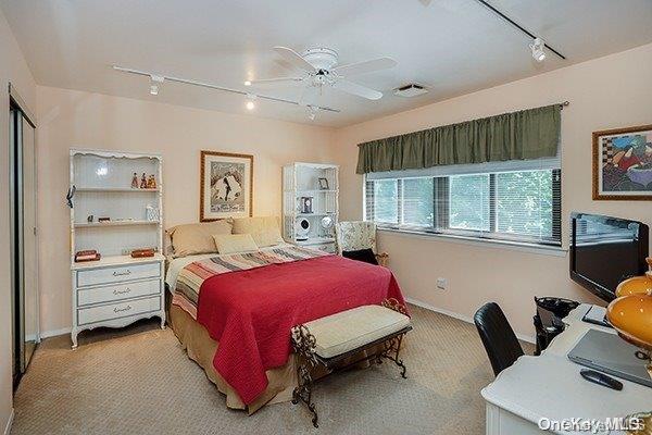 carpeted bedroom featuring track lighting and ceiling fan