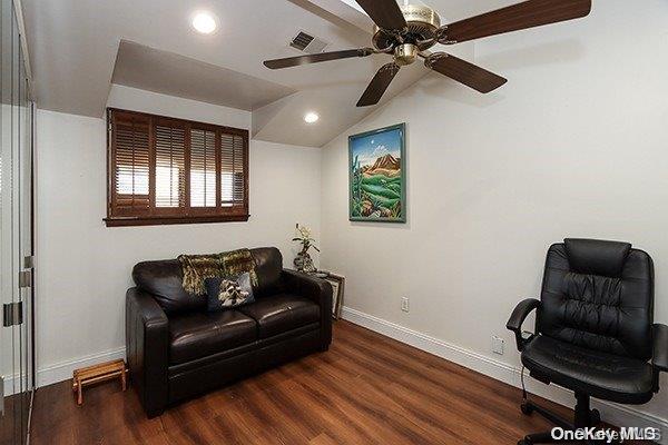 living area featuring ceiling fan, dark wood-type flooring, and vaulted ceiling