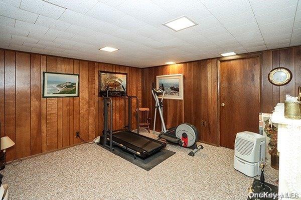 workout room with light colored carpet and wood walls