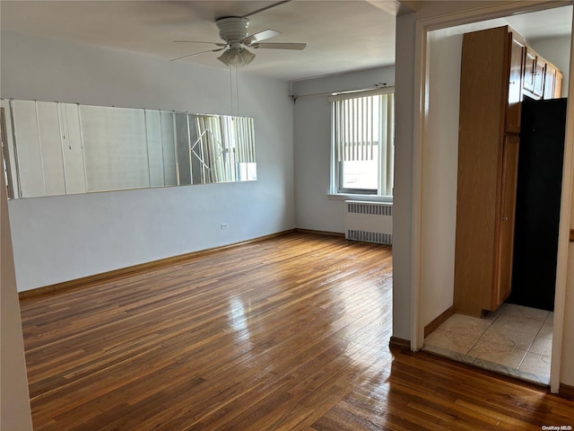 empty room with ceiling fan, radiator heating unit, and wood-type flooring