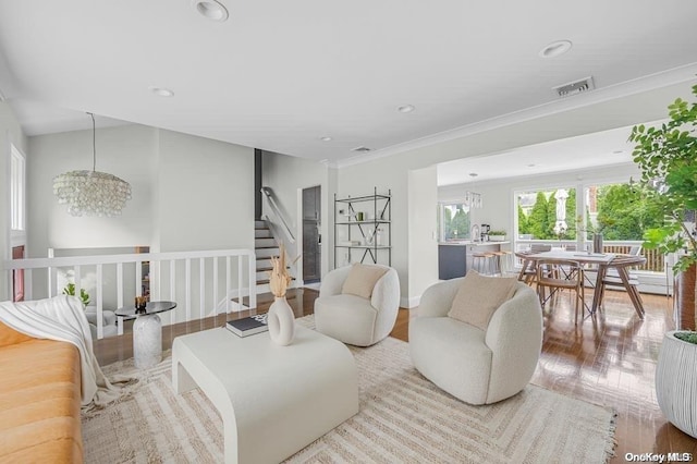 living room with a notable chandelier, light hardwood / wood-style floors, crown molding, and vaulted ceiling