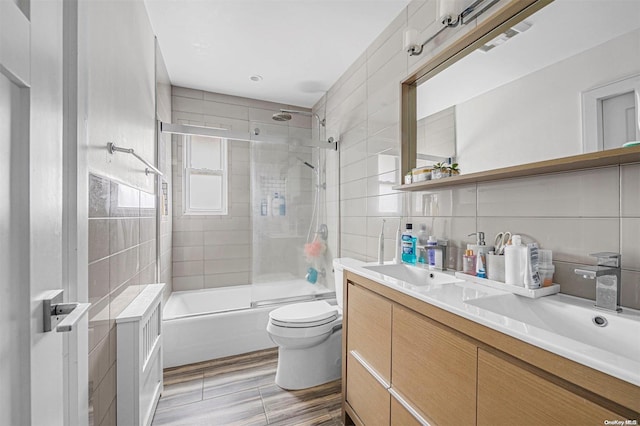 full bathroom featuring decorative backsplash, wood-type flooring, tile walls, enclosed tub / shower combo, and toilet