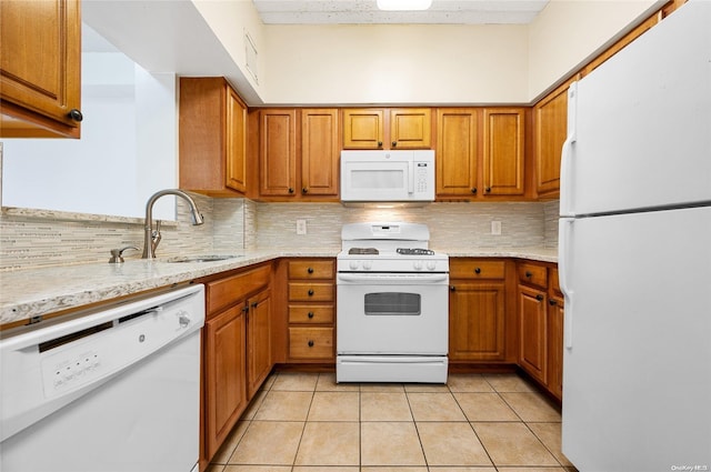 kitchen featuring light stone countertops, sink, white appliances, decorative backsplash, and light tile patterned floors