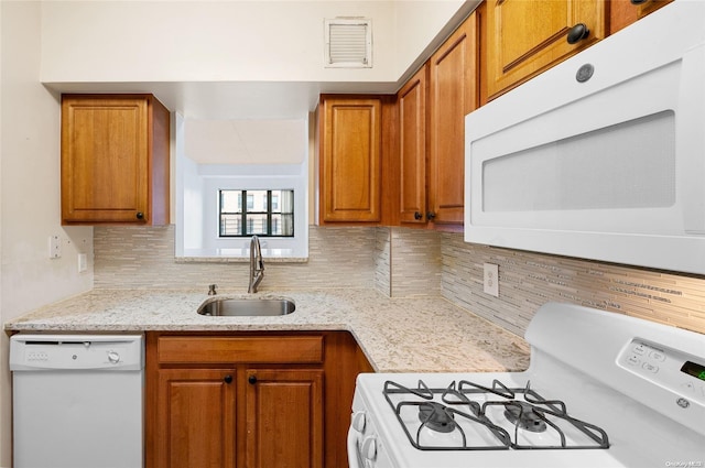 kitchen with decorative backsplash, white appliances, light stone counters, and sink