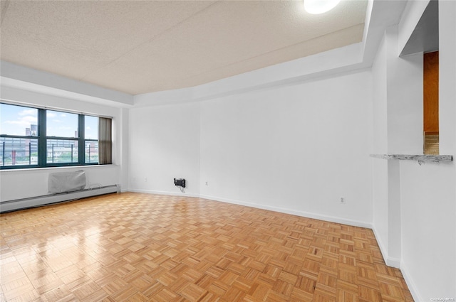 empty room featuring light parquet flooring, a baseboard radiator, and a textured ceiling