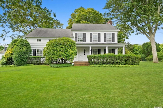 colonial-style house featuring a porch and a front yard