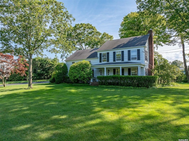 colonial home with a front yard and covered porch