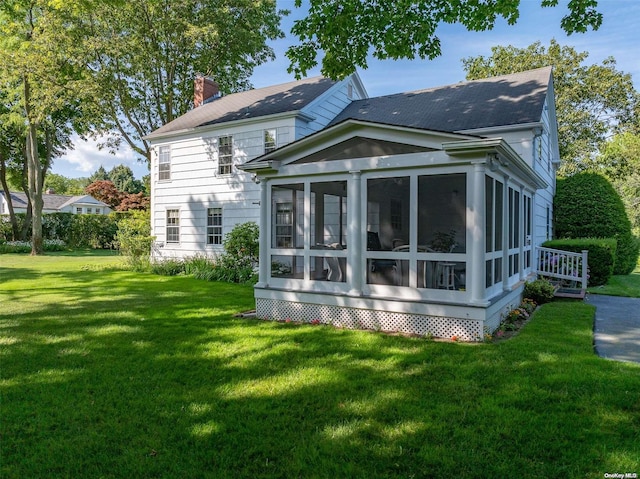 back of house featuring a lawn and a sunroom