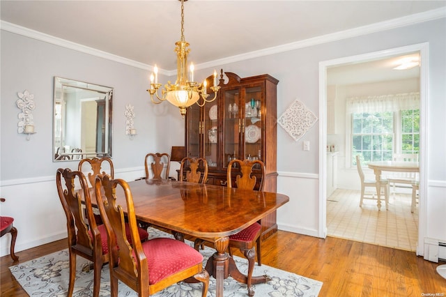 dining room with crown molding, a chandelier, and light wood-type flooring