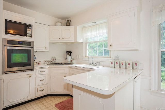 kitchen featuring stainless steel appliances, white cabinetry, a wealth of natural light, and sink