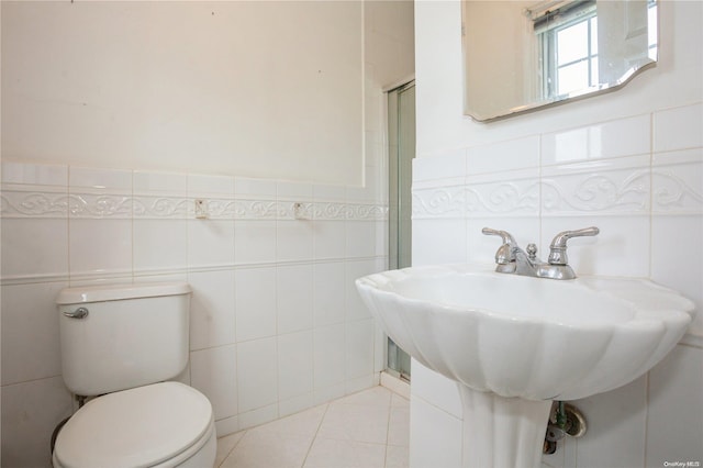 bathroom with sink, tile patterned flooring, tile walls, and toilet